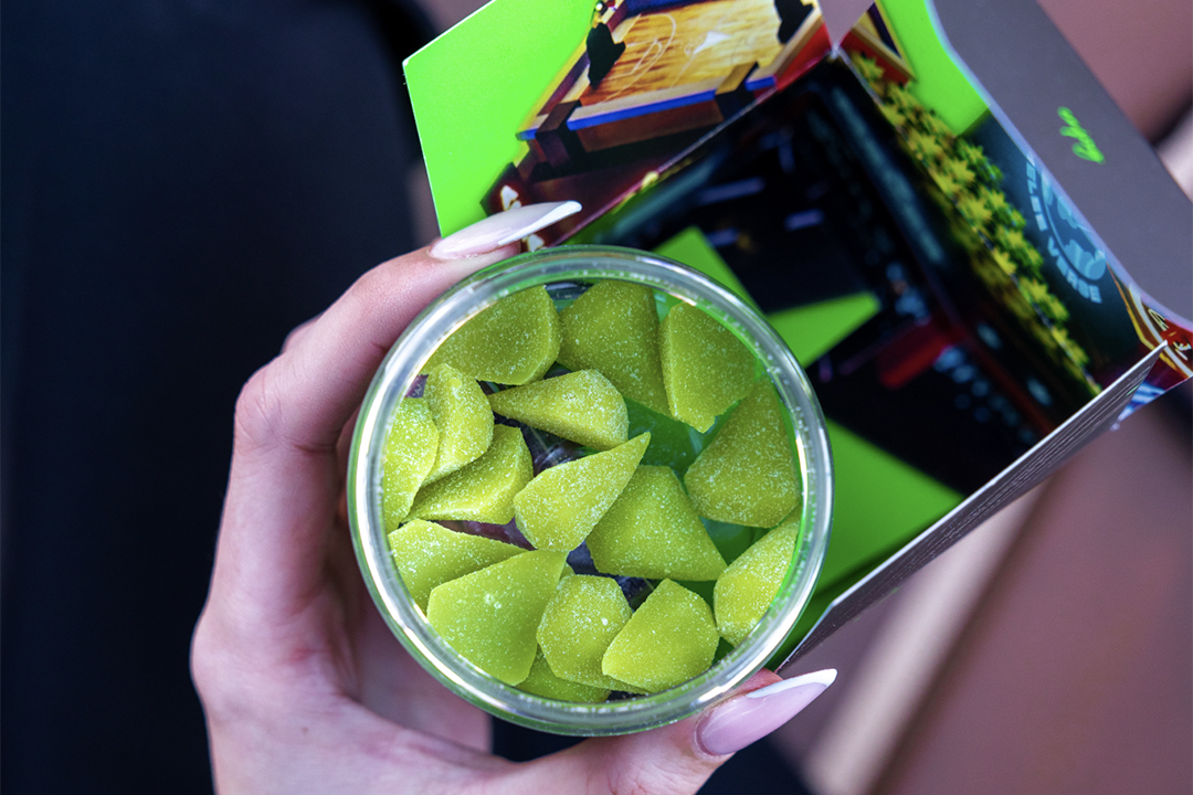 Top view of a woman holding an open jar of Melee Dose gummies.
